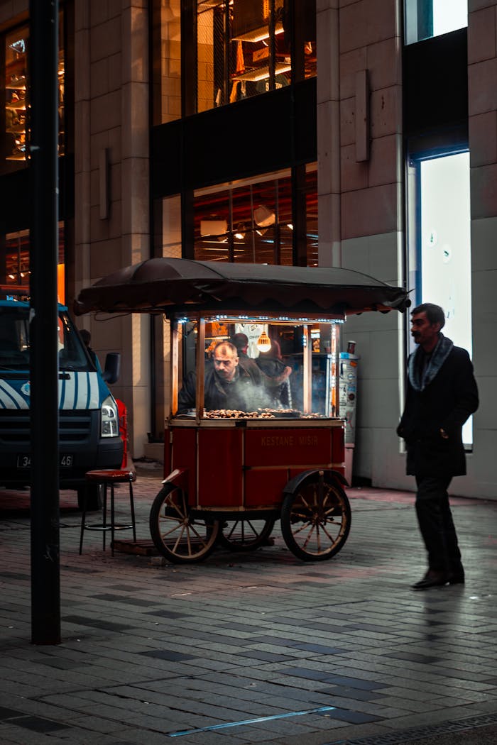 A street vendor sells roasted chestnuts at night in Istanbul's urban setting, under warm lights.